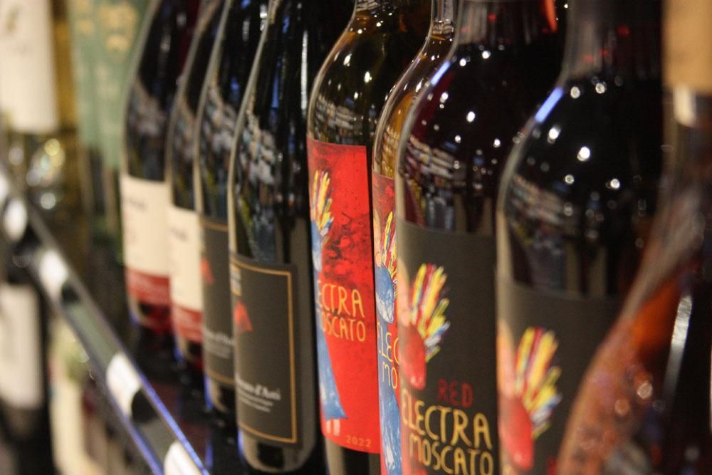 A close-up view of wine bottles lined up on a store shelf, highlighting labels like 