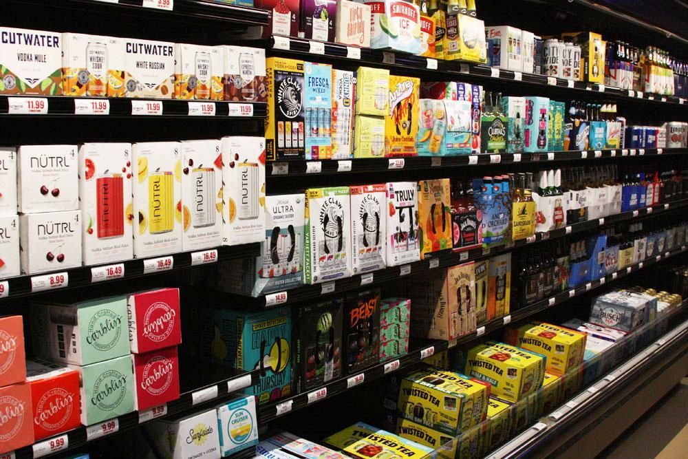 Shelves filled with various brands and flavors of canned alcoholic beverages and beer in a store aisle.