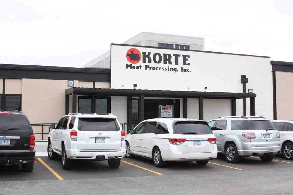 Exterior view of Korte Meat Processing, Inc. building with several parked vehicles in front.