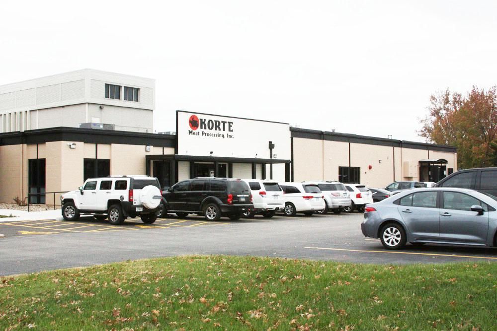 A Korte Construction building with a parking lot containing several SUVs and cars on a cloudy day.