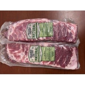Two vacuum-sealed packages of raw pork ribs labeled Prairie Fresh Natural on a brown wooden surface.