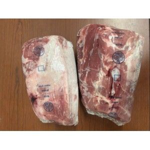 Two large, vacuum-sealed cuts of raw pork shoulder resting on a wooden surface.