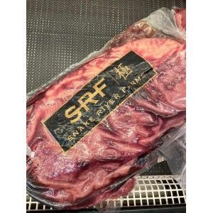A vacuum-sealed slab of marbled raw beef labeled with the Snake River Farms 
