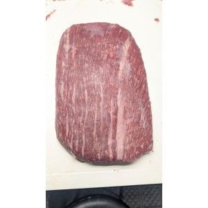 A raw, trimmed piece of beef roast with visible marbling resting on a white cutting board.
