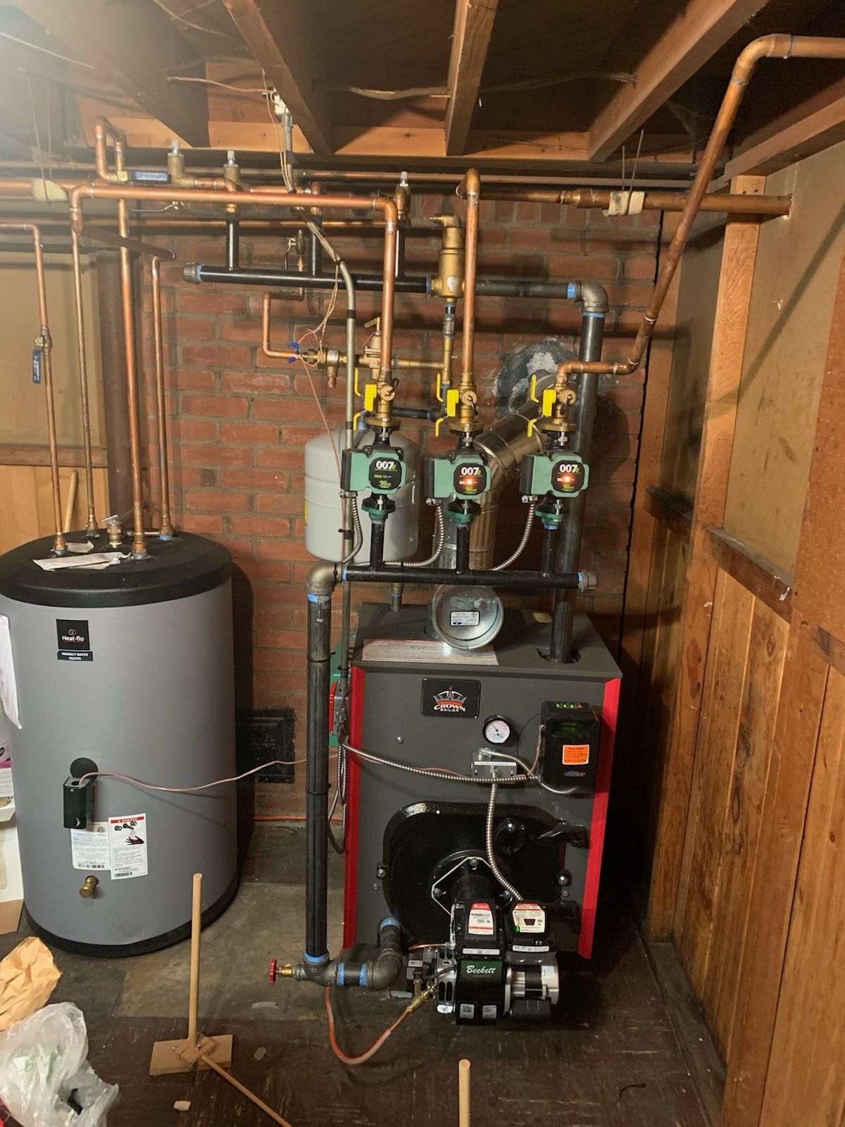 Basement mechanical room with water heater, boiler, pipes, pumps, and exposed ductwork