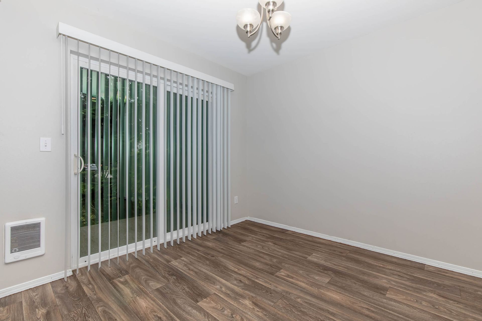 An empty room with sliding glass doors and blinds.