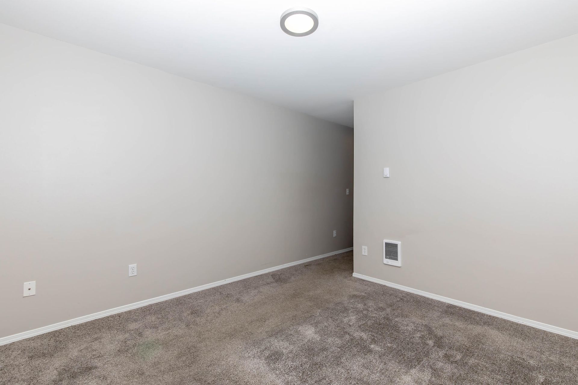 An empty room with a carpeted floor and white walls.