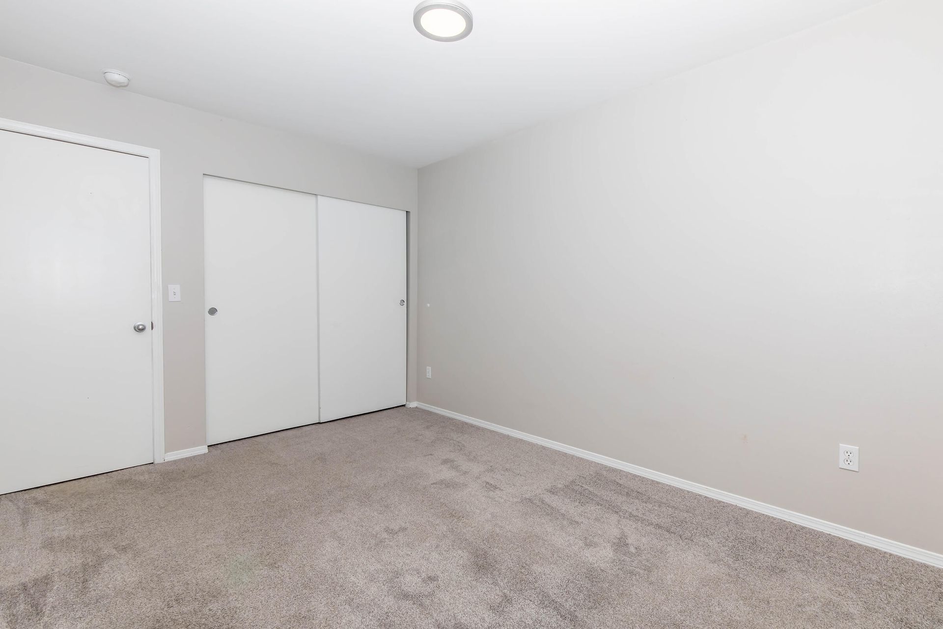 An empty bedroom with a carpeted floor and white walls.