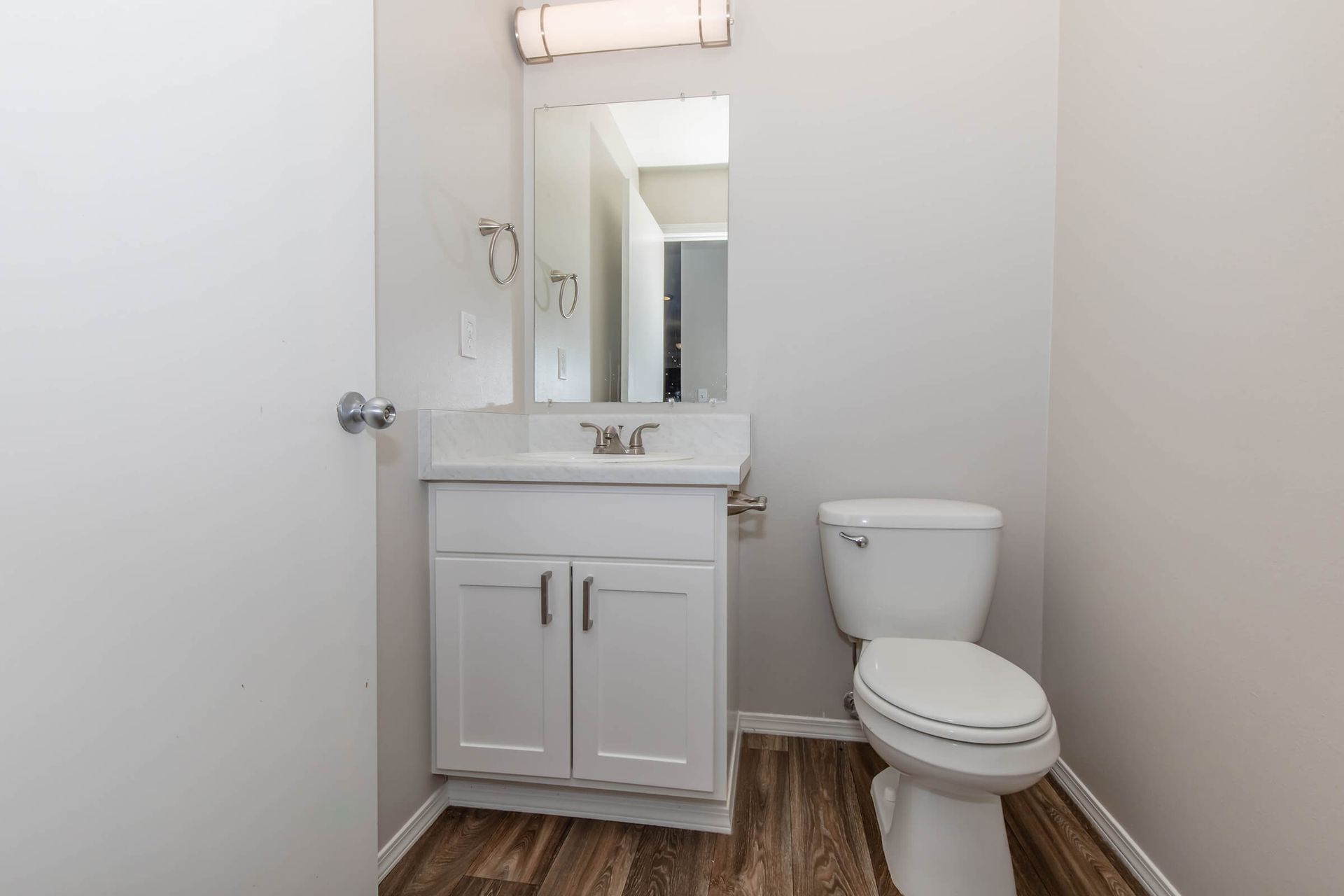 A bathroom with a toilet , sink and mirror.