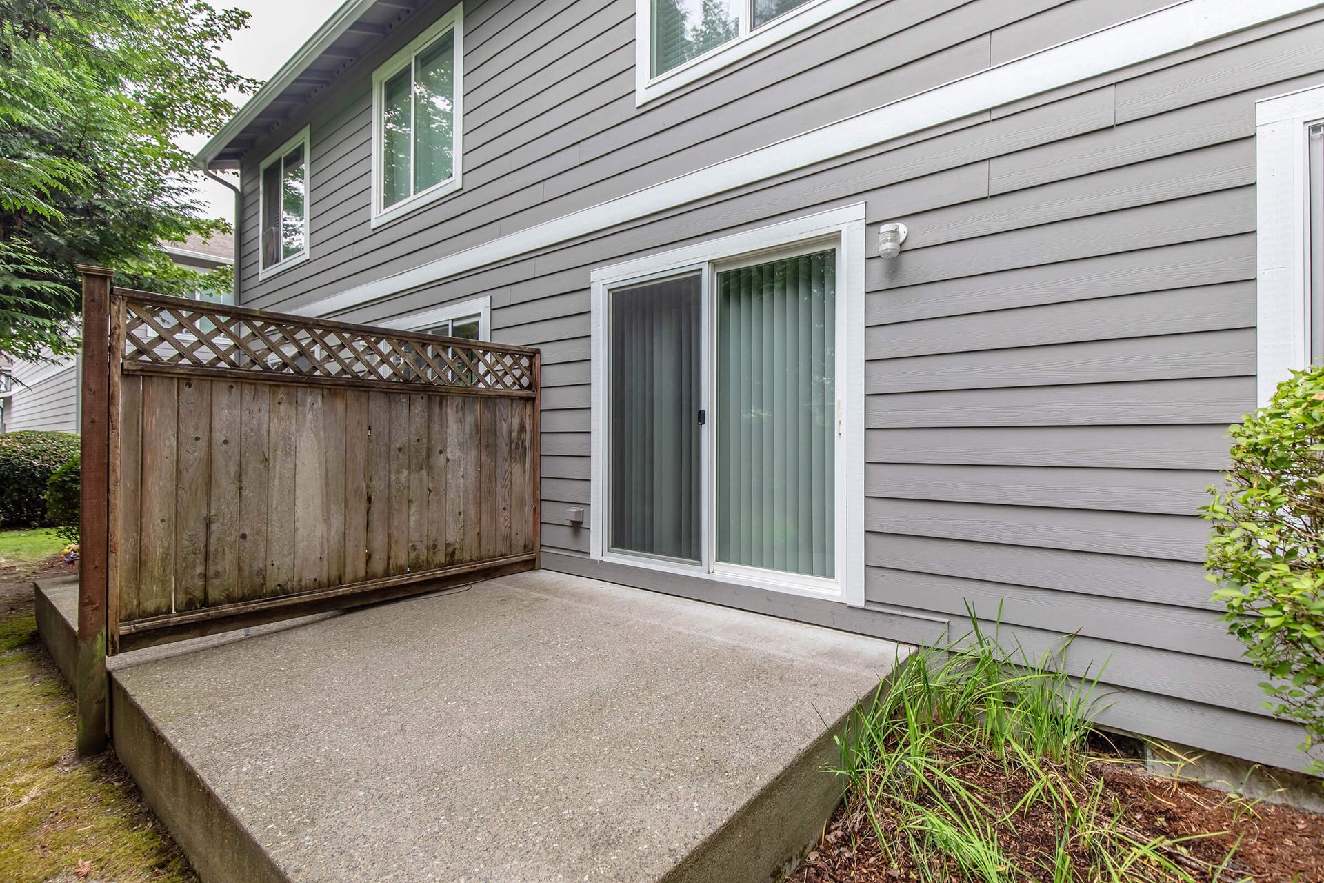 The backyard of a house with a patio and sliding glass doors.