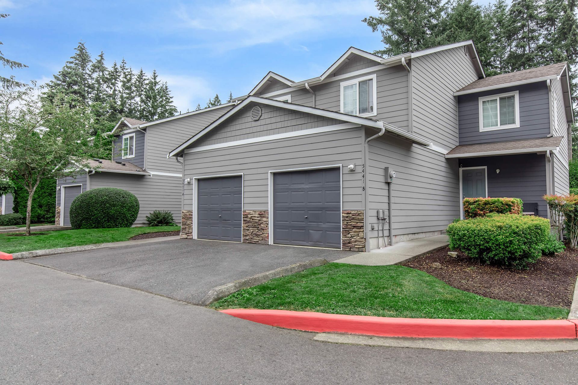 A house with two garage doors and a red curb