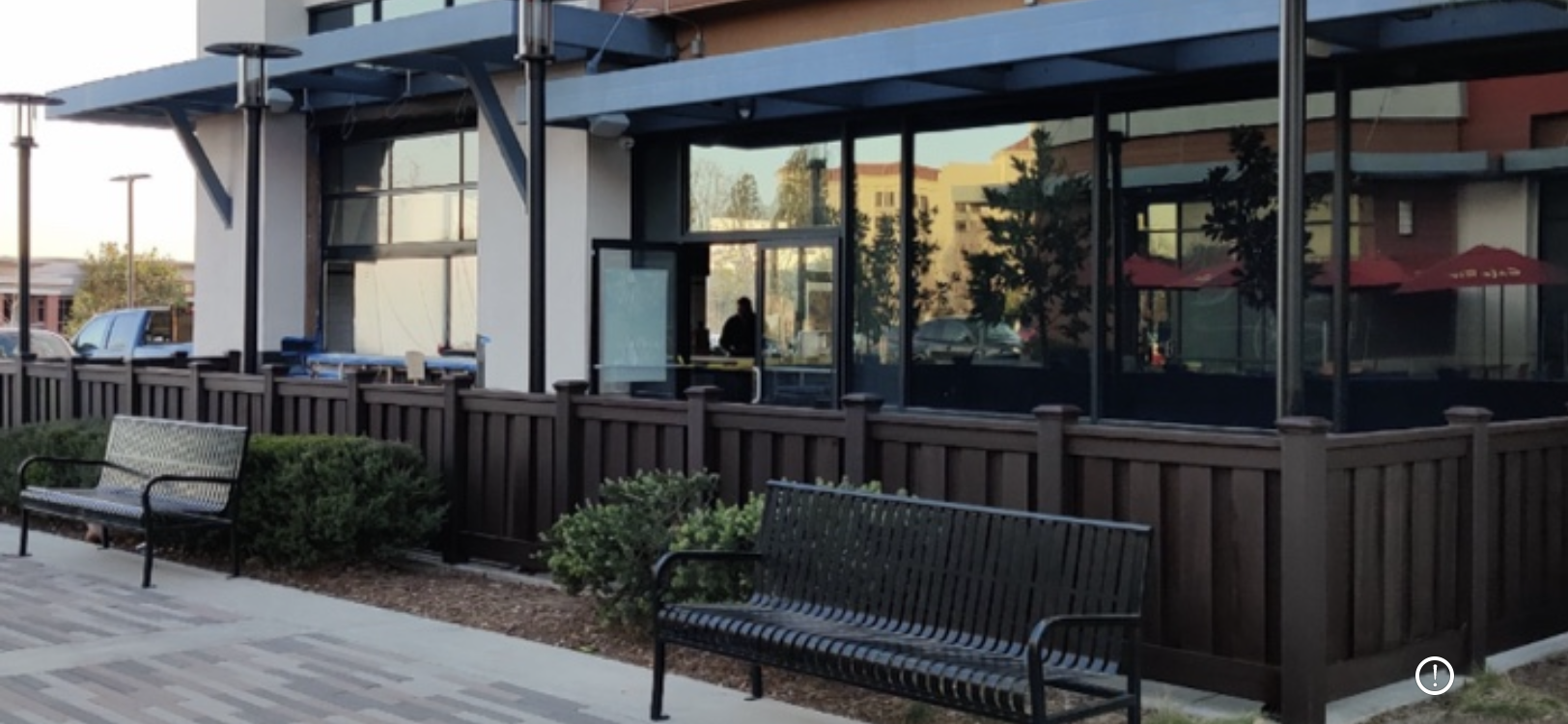 Restaurant exterior with a glass facade, outdoor seating, and two benches in front.