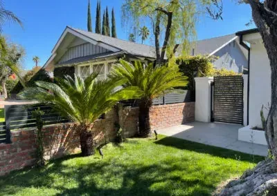 Black metal fence overlooking a suburban neighborhood with houses and trees under a warm sunset.