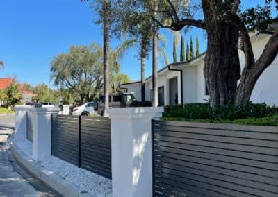 Black wrought-iron fence atop a concrete wall against a cloudy sky.