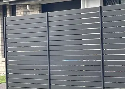 Black metal fence overlooking a suburban neighborhood at sunset.
