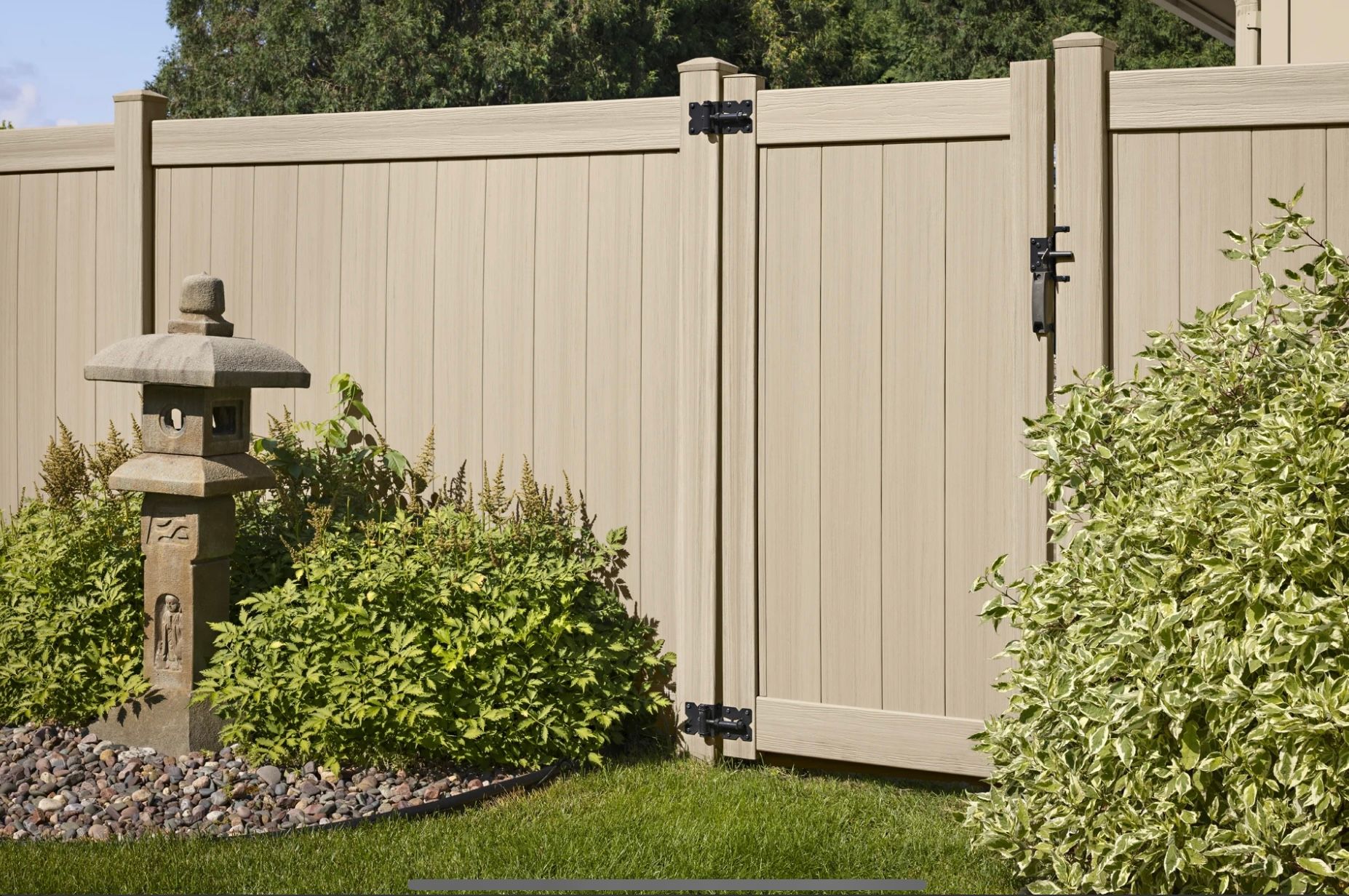 Gray horizontal privacy fence in front of a building on a sunny day.