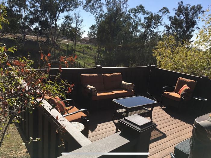 Wooden fence alongside a paved path with trees in the background.