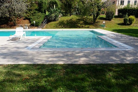 una piscina in un giardino e una sdraio di plastica di color bianco