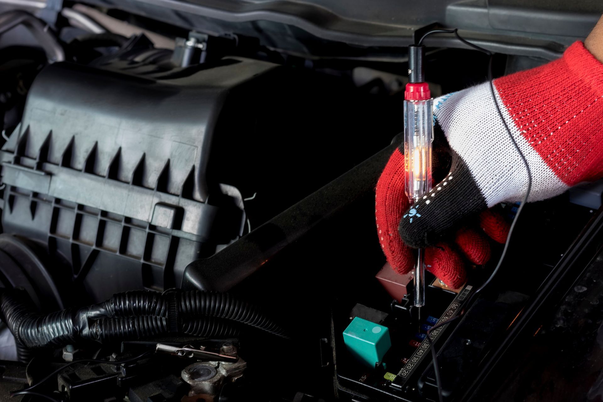 A person wearing red gloves is working on a car engine.