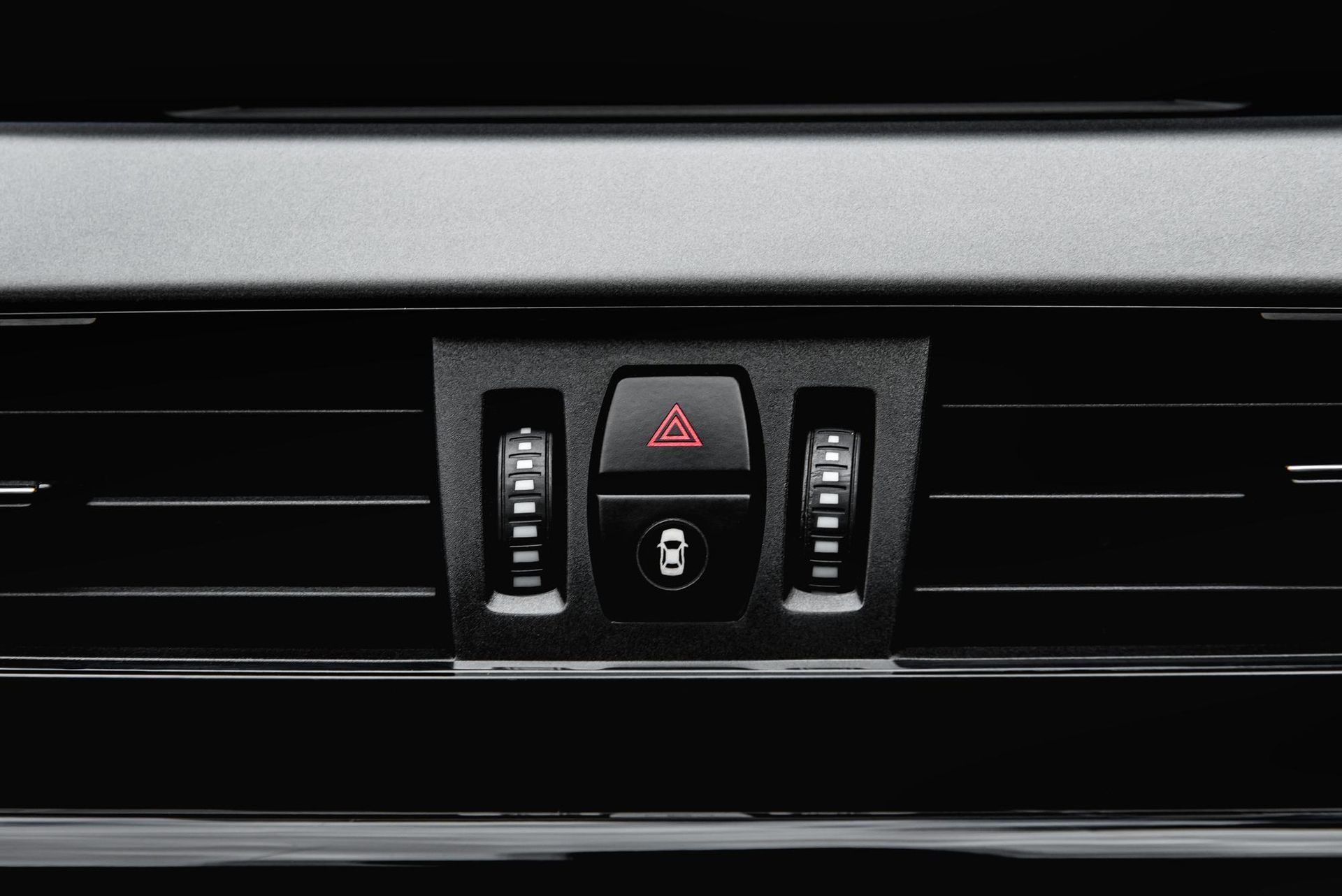 A close up of a car air vent with a red triangle on it.