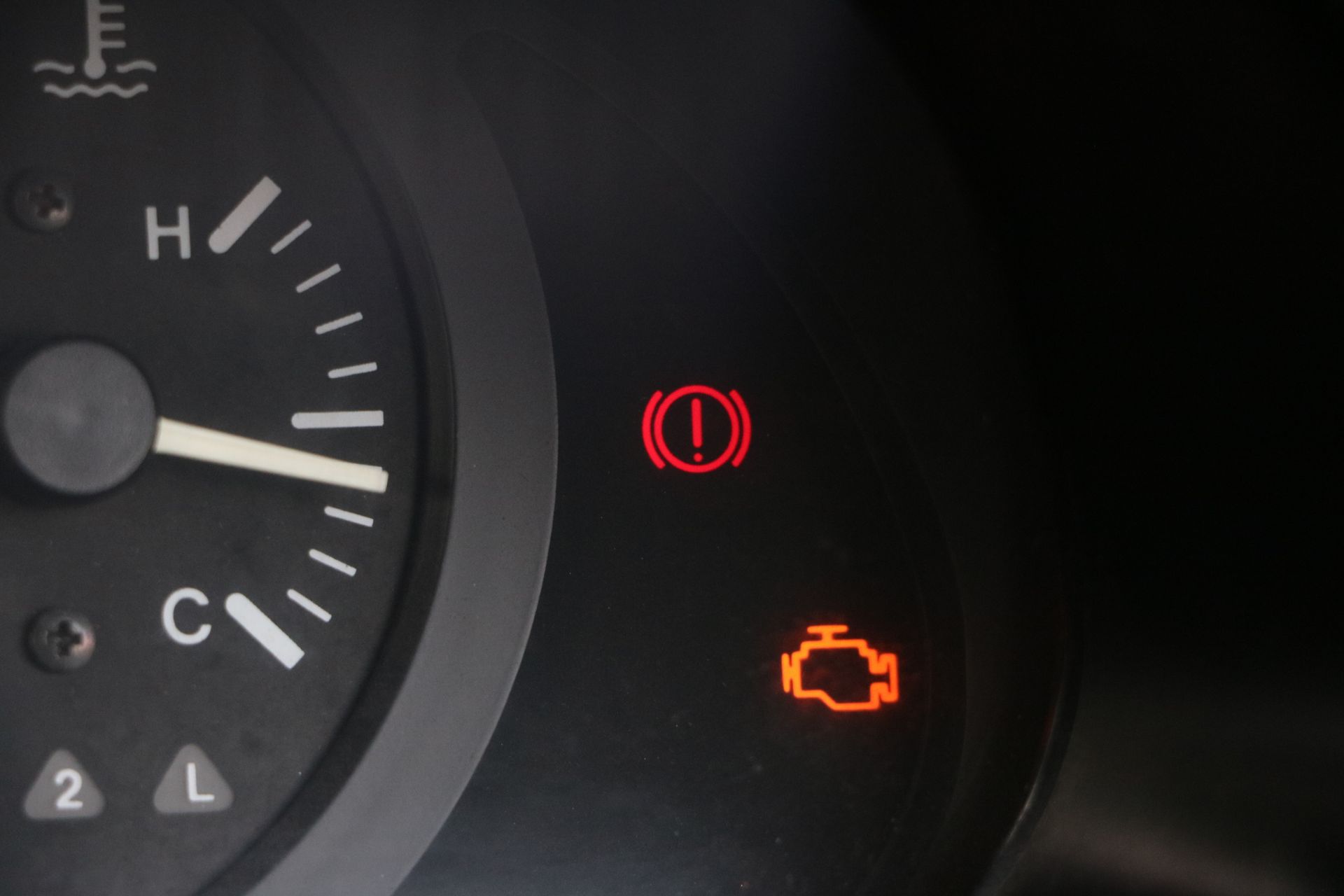 A close up of a car dashboard with a red warning light on