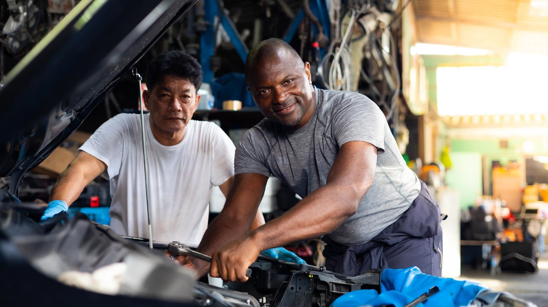 Two men are working on a car in a garage.