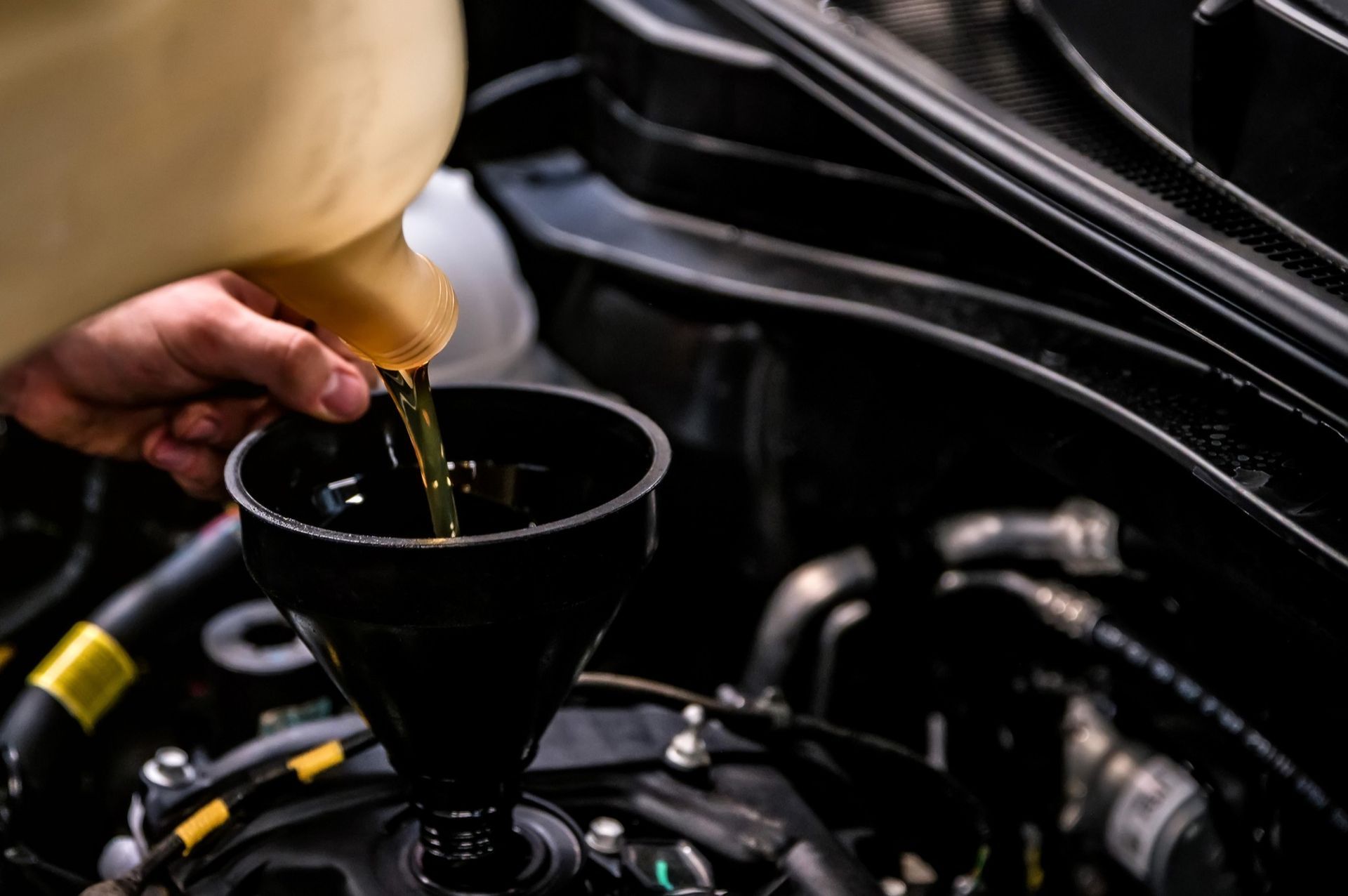 A person is pouring oil into a funnel in a car.