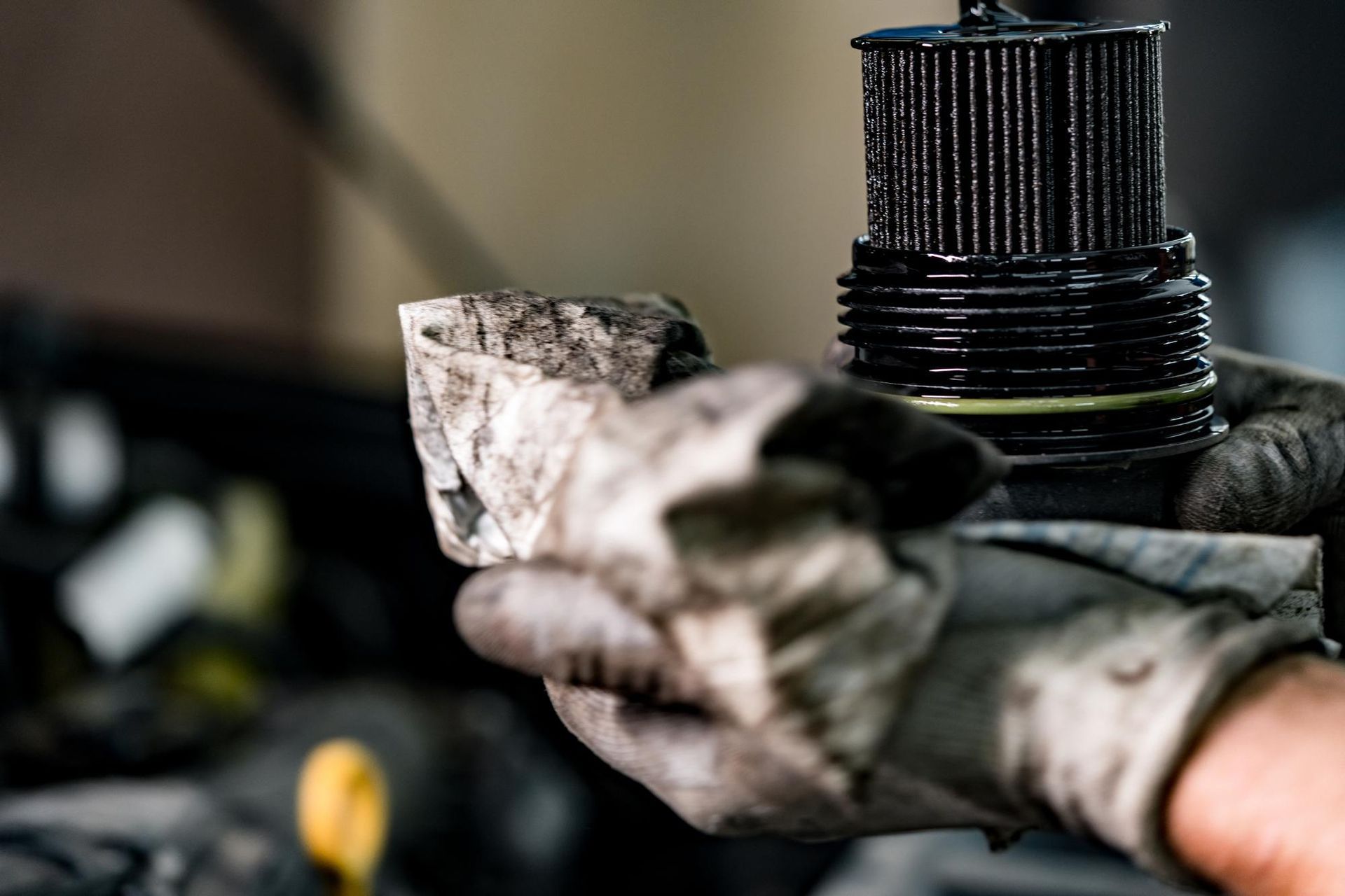 A person is holding a dirty oil filter in their hand.