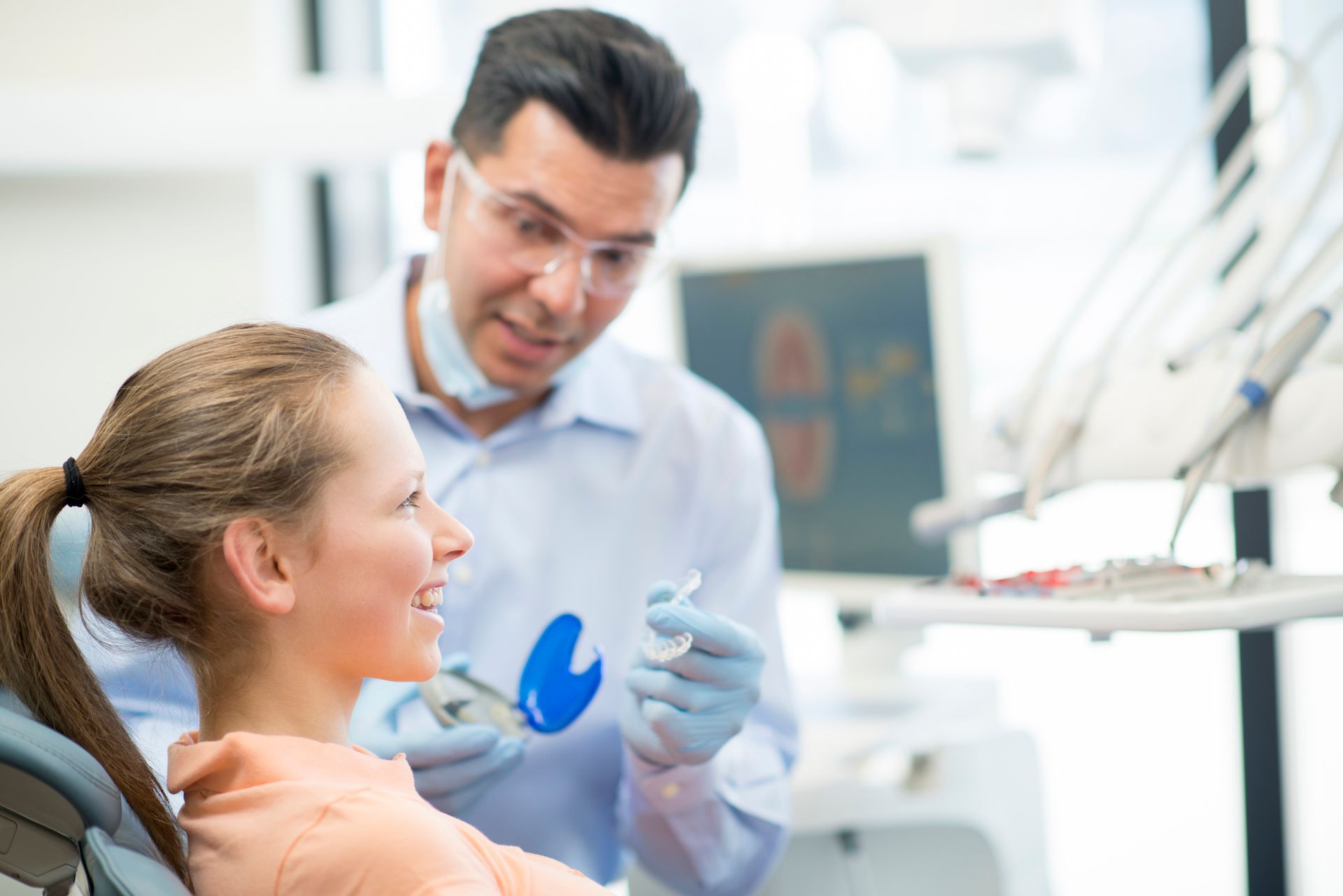 A teenager is receiving her new Invisalign braces at Nicholas J. Hurley D.D.S., P.A. in High Point, 