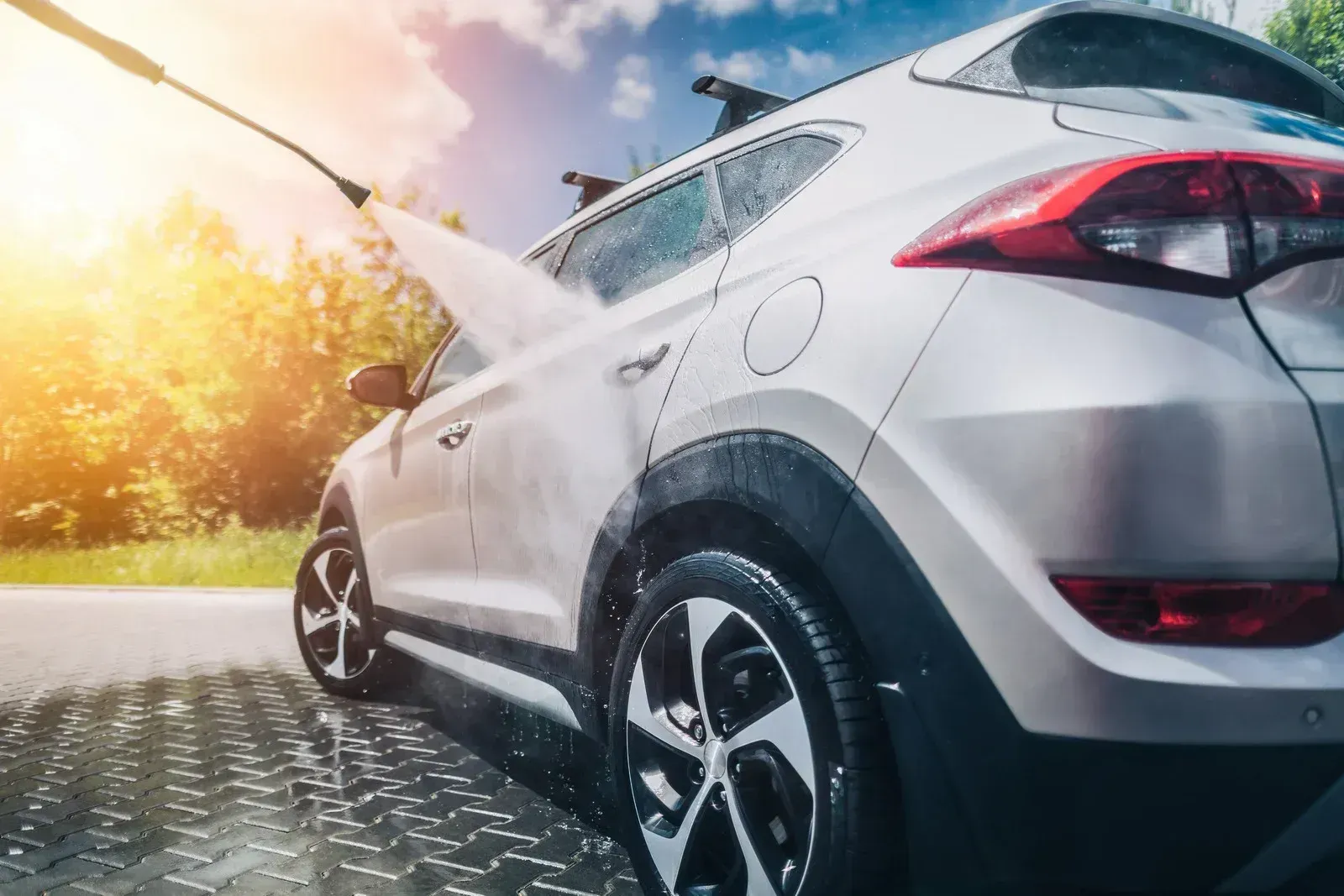 A white car is being washed with a high pressure washer.