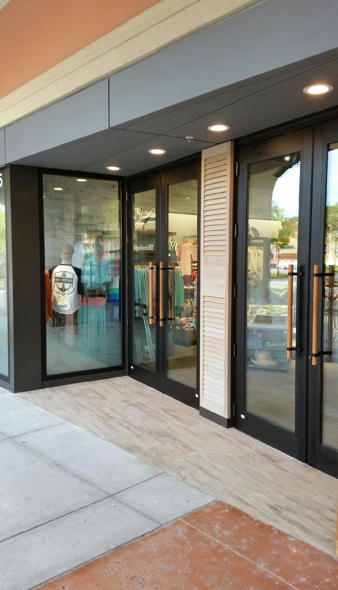 Storefront with glass doors, long handles, and a light-colored panel.