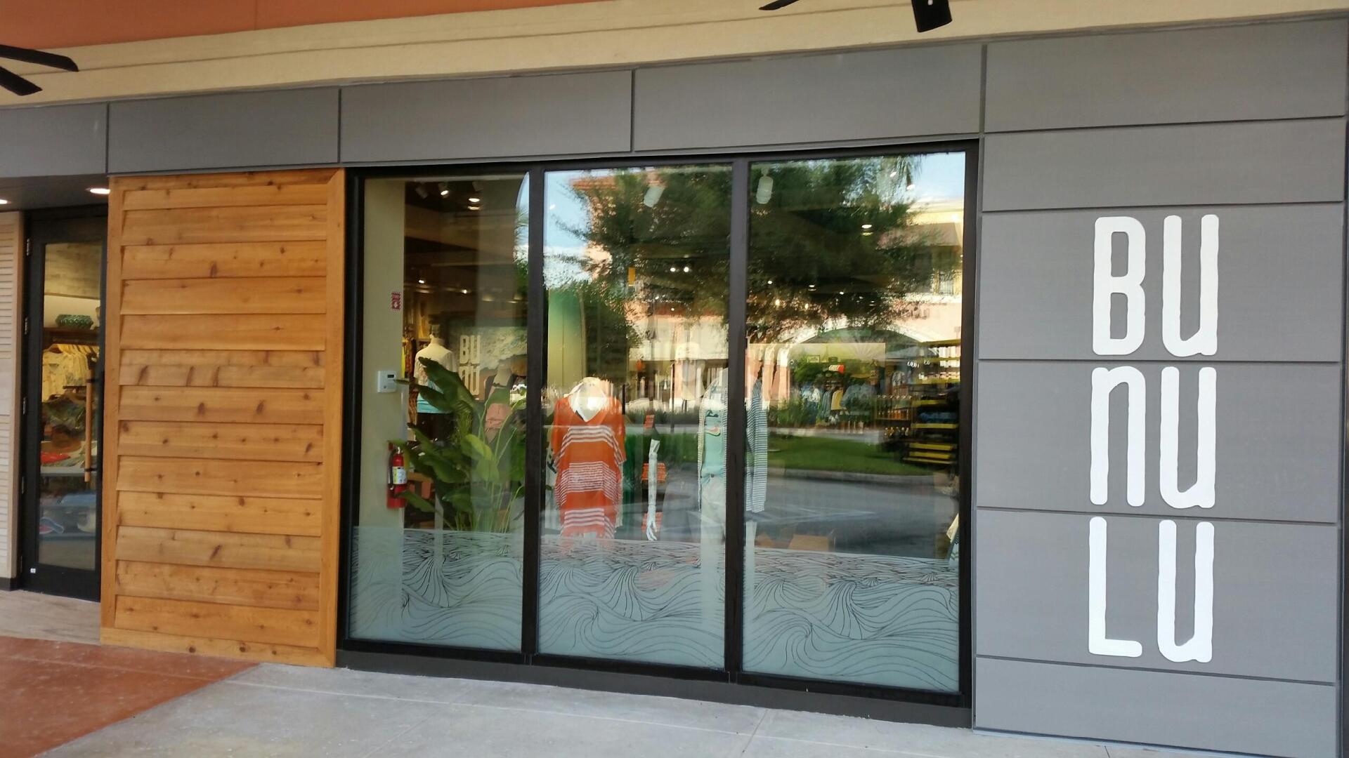 BUNULU storefront with a wooden wall, glass doors, and gray facade.