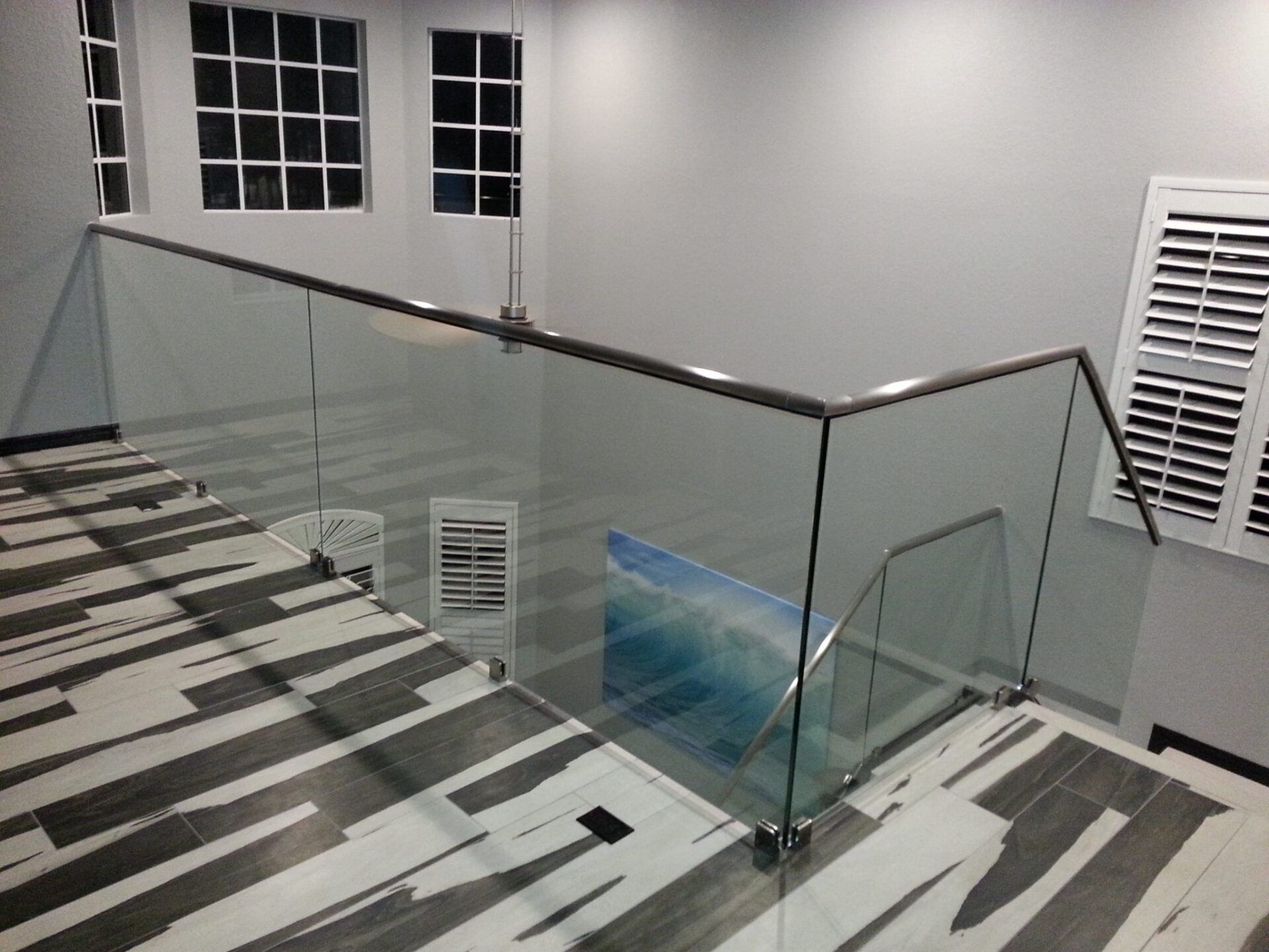 Modern staircase with glass railings and patterned flooring.