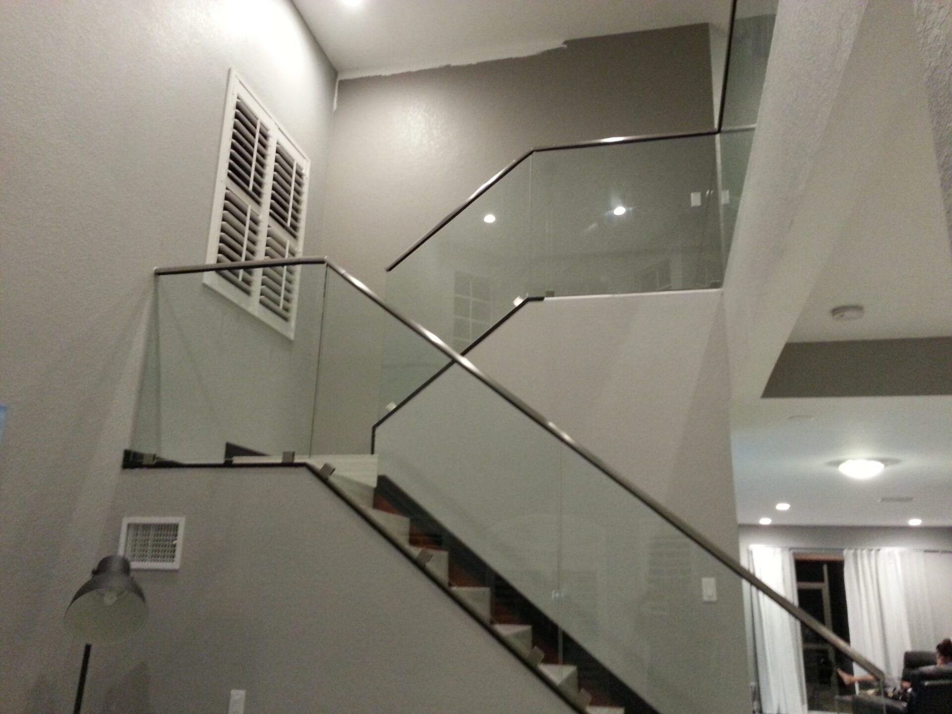 Interior staircase with glass railings and gray walls. Wooden steps.