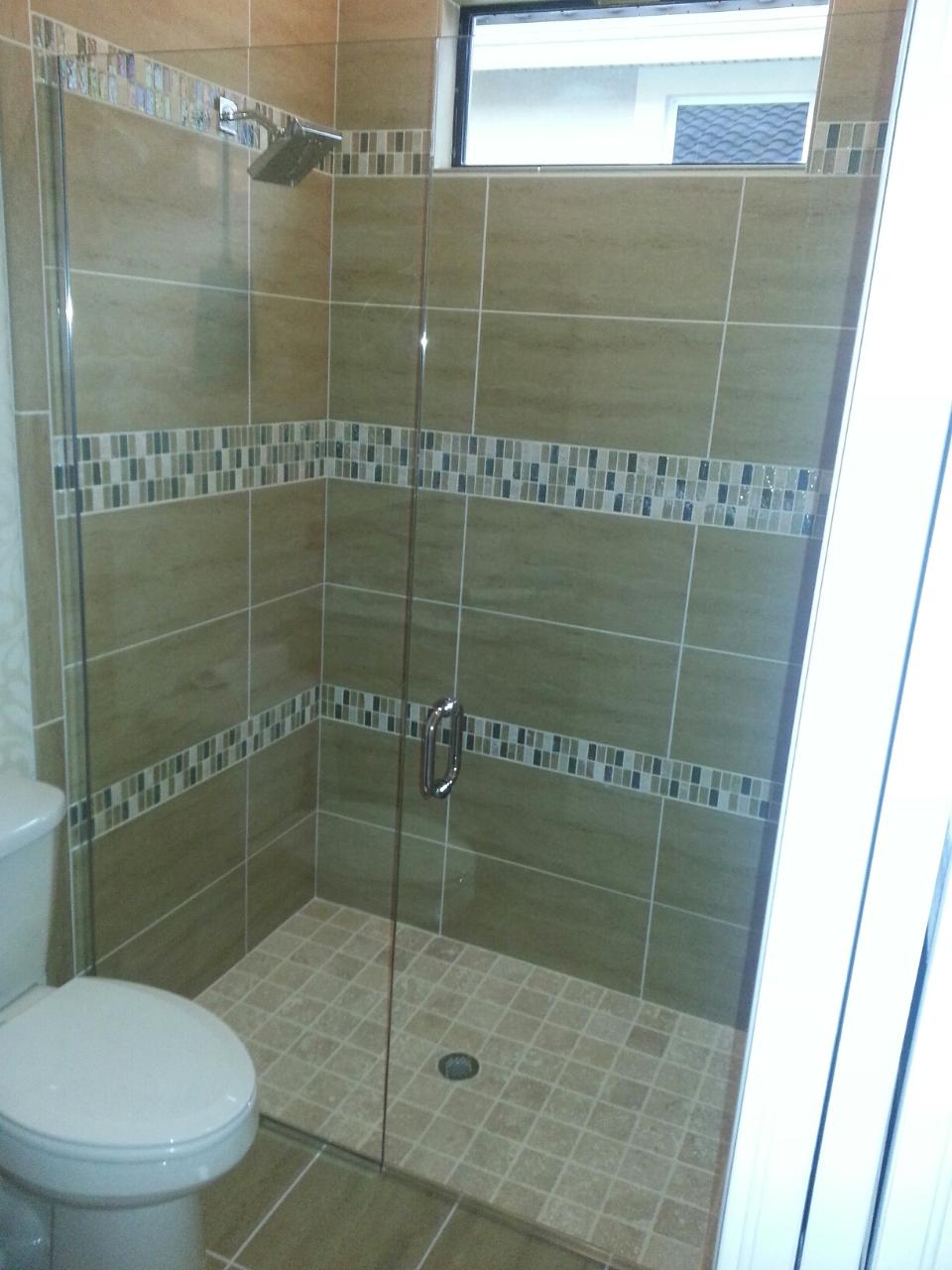 Shower with beige tiles and glass door, toilet visible.