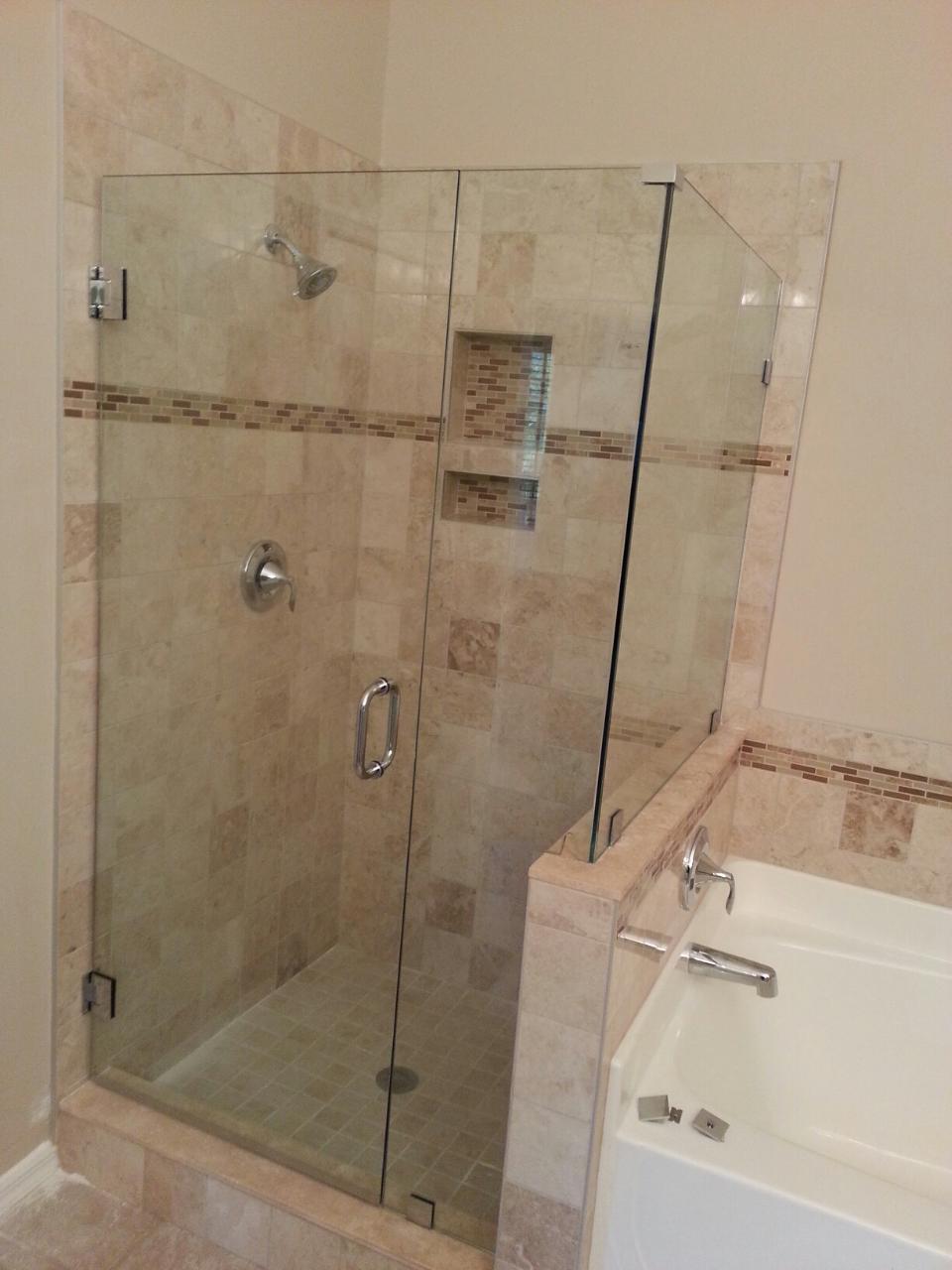 Shower with glass doors and beige tile. Tub is visible to the right.