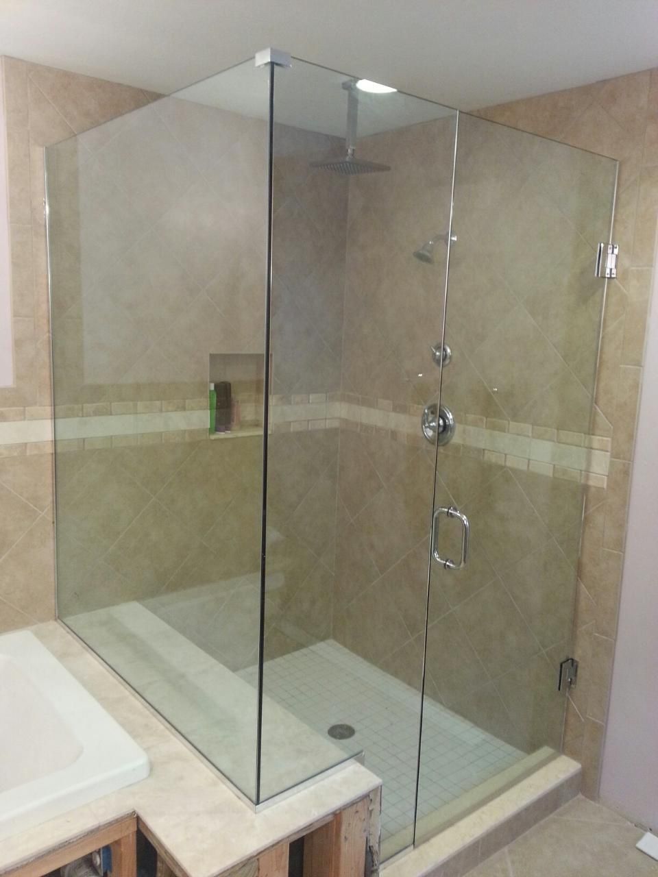 Glass shower enclosure with beige tile walls, a white shower base, and chrome fixtures.