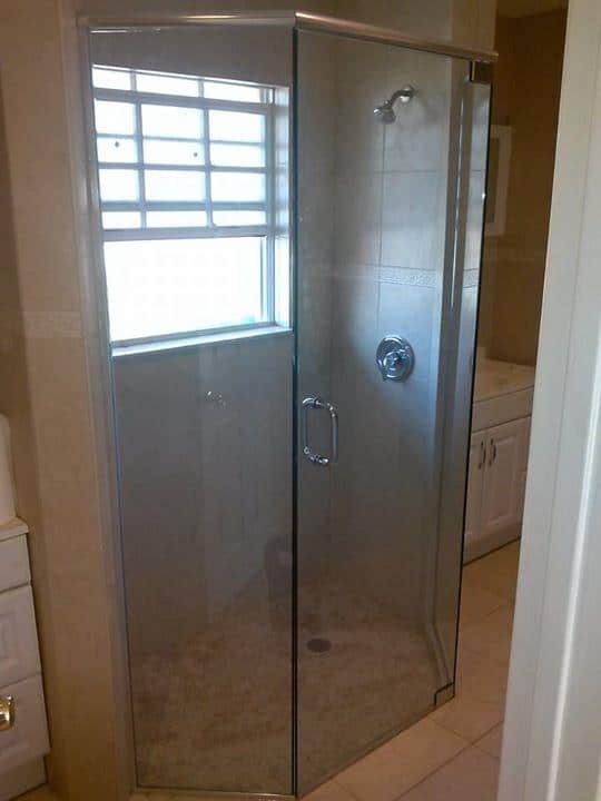 Glass-enclosed shower stall with a window. Chrome fixtures, light-colored walls, and floor.