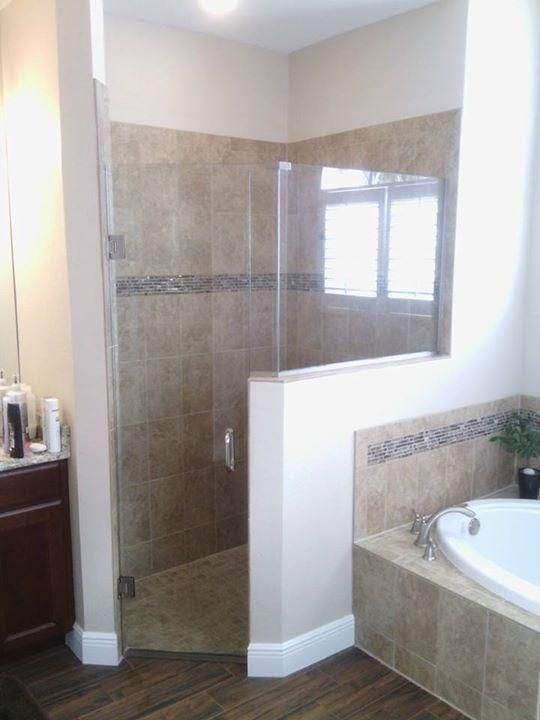 Bathroom with a glass shower, beige tile, and a wooden floor.
