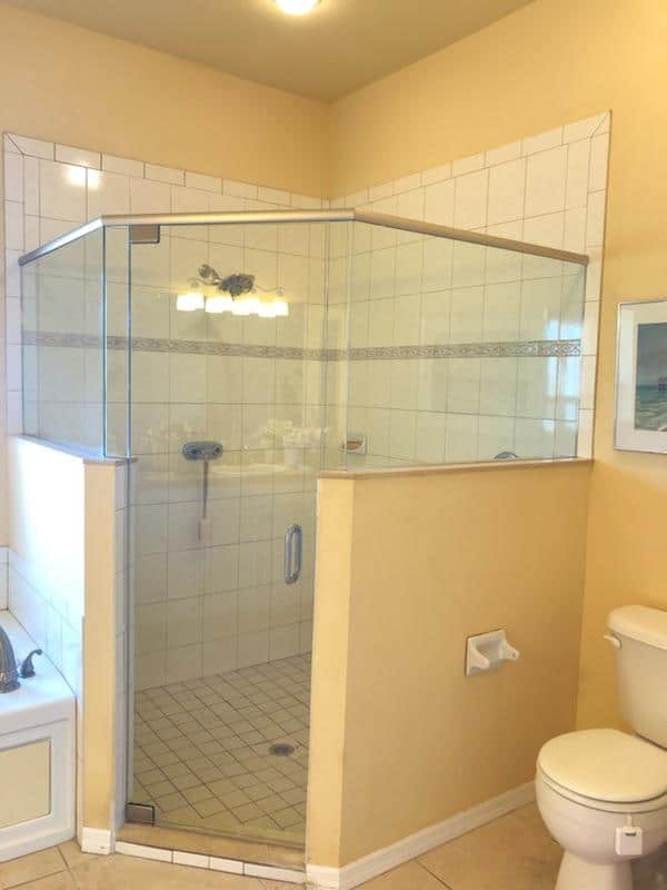 Bathroom with a clear glass shower enclosure, white tile walls, and a toilet.