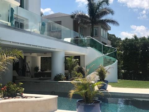Modern home with spiral staircase, glass railings, and a pool.