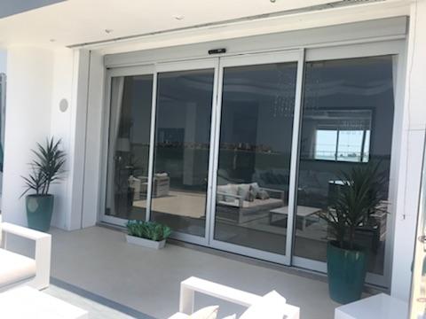 Sliding glass doors to a modern interior with seating, plants, and a view.