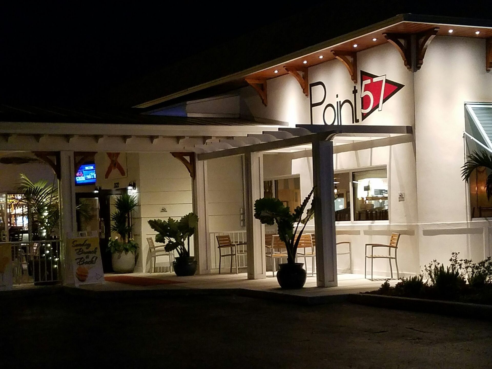 Night view of Point 57 restaurant exterior with lit sign and outdoor seating.