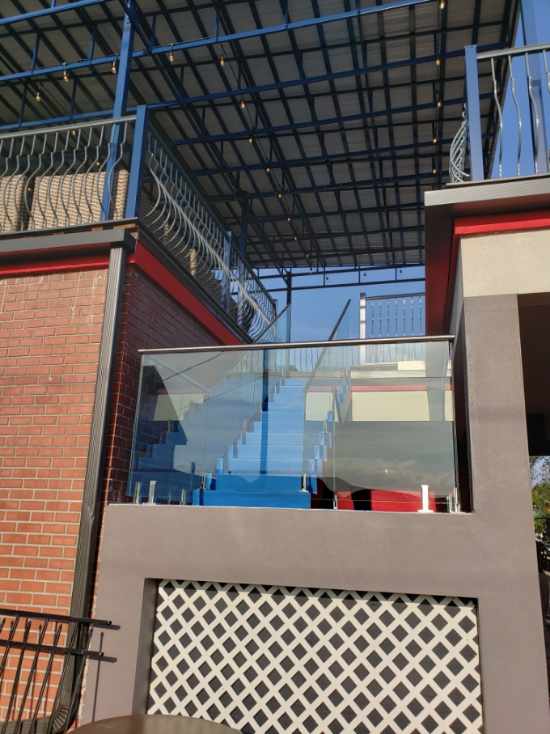 Building exterior with glass railings, brick wall, metal roof, and patterned paneling.