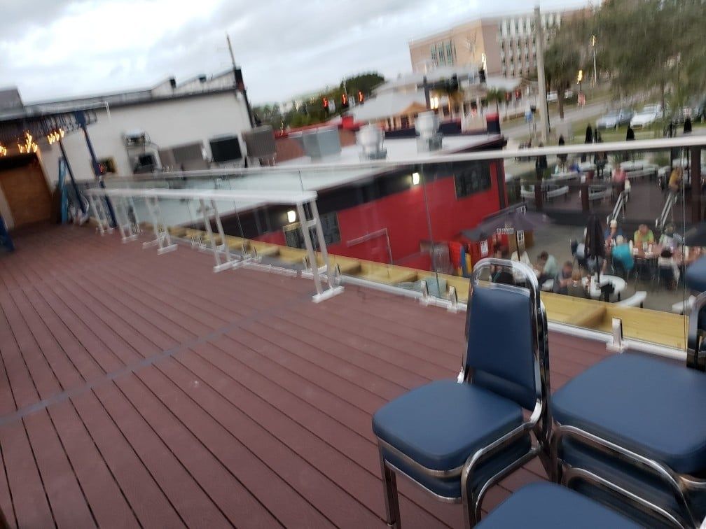Rooftop deck with blue chairs overlooking a restaurant. Red building visible.