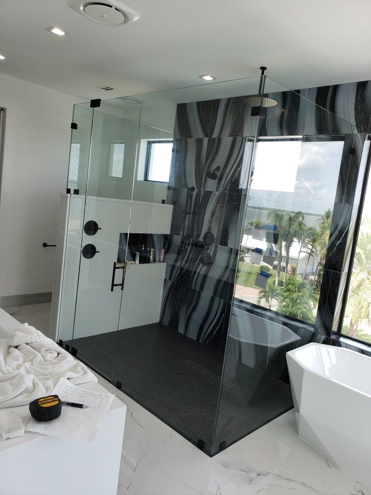 Modern bathroom with glass shower, patterned accent wall, and a white bathtub.