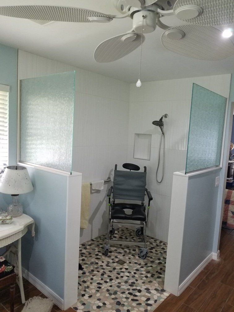 Wheelchair-accessible shower with glass panels and pebble floor; wheelchair inside.