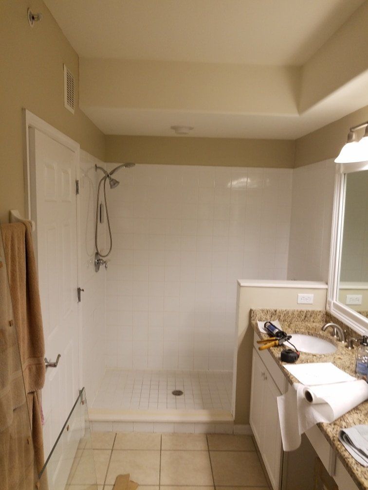 Bathroom with a white shower stall, beige walls, and a white vanity.