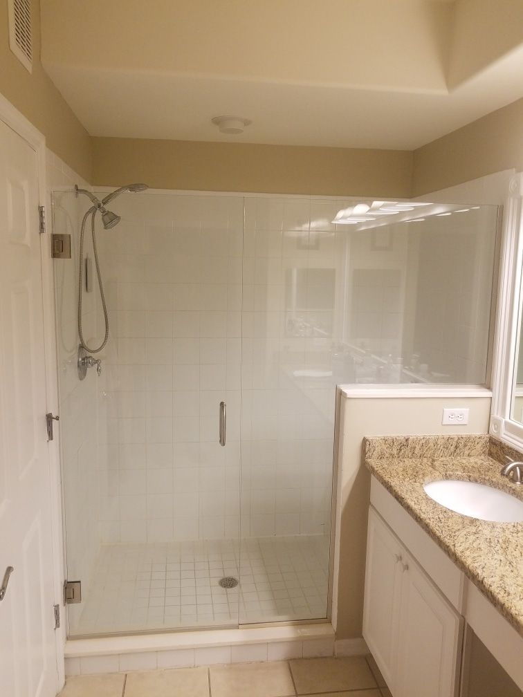 Bathroom with a glass shower, white tile, and a vanity with granite countertop.