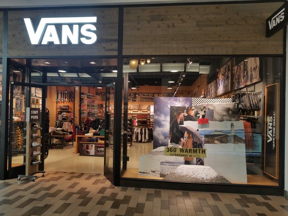 Vans store front with lit-up logo, glass doors, and interior merchandise visible.